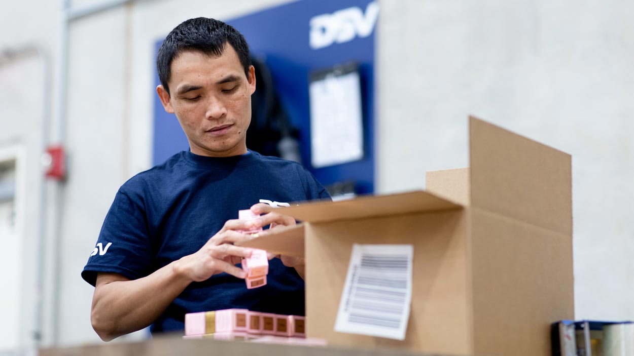 DSV medarbeider pakker varer i en eske.